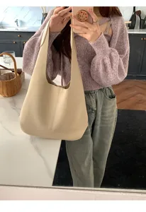 Detailed shot of a minimalist beige soft leather hobo shoulder bag in a stylish home setting.
