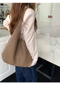 Detail view of the brown soft leather shoulder bag, highlighting its slouchy texture and capacity.