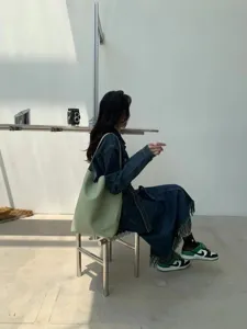Detail shot showing the light green PU bucket shoulder bag worn by a model in a minimal studio.