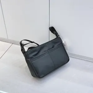 Black nylon crossbody bag detail view, multi-pocket design, adjustable strap and zipper.
