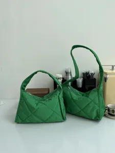 Detailed display of green quilted nylon shoulder bag, puffy crescent casual handbag.