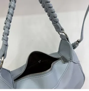 Close-up detail of light blue women shoulder handbag with braided handle and metal zipper.