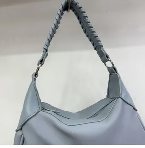 Detailed shot of light blue women's handbag featuring braided handle and metal hardware.