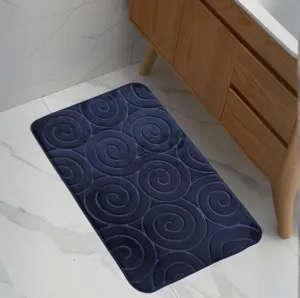 Detailed view of the dark blue embossed swirl pattern bath mat on tile floor.