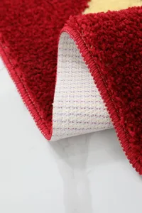 Detalle de alfombra jacquard de dibujos animados, base antideslizante y superficie de felpa roja.