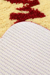 Detalle de alfombra antideslizante suave con superficie copetuda y base texturizada.