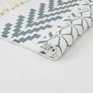 Nordic style woven cotton linen rug detail shot, showing geometric pattern and fringe edge.