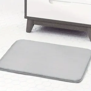 Detailed view of a soft gray memory foam bath mat placed on bathroom tiled floor.
