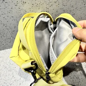 Detailed view of small yellow crossbody bag interior, featuring zipper and mesh pockets.