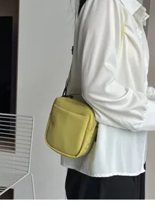 Yellow small crossbody bag detail showing zipper closure, front pocket and adjustable strap.
