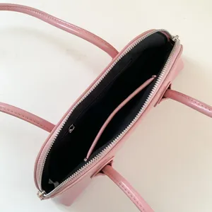 Pink leather undershoulder bag with zipper top, dual interior compartments and shoulder strap.