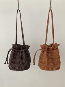 Detailed shot of stylish pleated faux leather drawstring shoulder bags in dark brown and caramel.