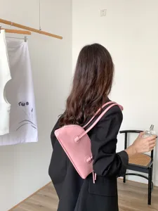 Chic pink shoulder baguette bag with long strap, stylish retro design for everyday wear.