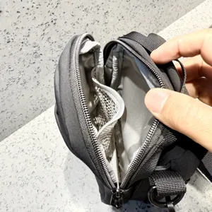 Detailed view of black small crossbody bag interior, mesh pocket, and zipper structure.