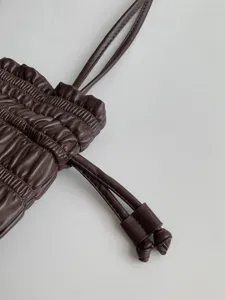 Dark brown pleated leather bag detail showcasing the exquisite drawstring and knot design.