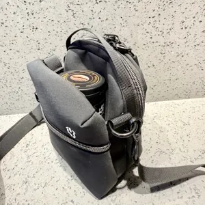 Detail view of lightweight black crossbody phone bag, compact design with zipper and strap.