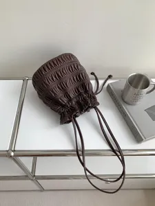 Detail view of brown ruched bucket bag texture, minimalist style background prop details.