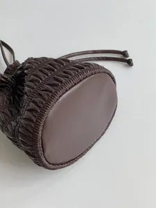 Brown leather gathered drawstring bucket bag detail close-up showing soft texture and bottom.