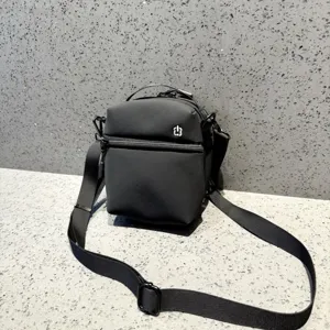 Close-up detail of a black mini crossbody shoulder bag with zipper and adjustable strap.