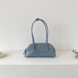 Closeup detail of light blue leather baguette shoulder bag, minimalist aesthetic style.