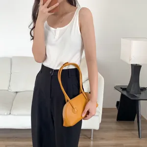 Detail shot of a stylish yellow shoulder bag with long handle, featuring chic baguette design.