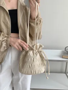 Detailed view of cream leather gathered drawstring bucket handbag with stylish pleated design.