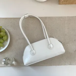 Detail view of white shoulder baguette bag, stylish long handle shell handbag design.