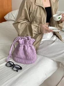 Detailed shot of purple pleated drawstring bucket bag with gathered design for daily chic look.