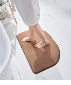 Soft brown semi-circular bath mat detail, highly absorbent and anti-slip for bathroom floor.