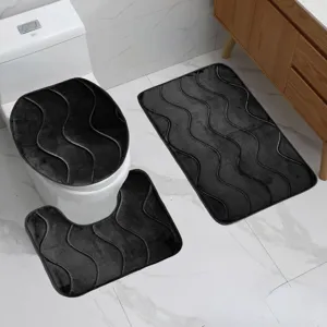 Dettaglio del set di tappetini da bagno con superficie morbida e struttura a onde scure.