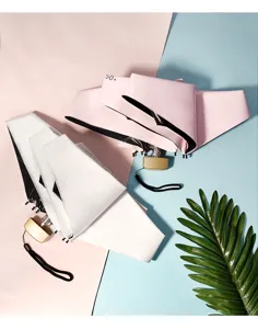 Closeup view of compact mini folding sun umbrellas in white and pink with UV protection details.