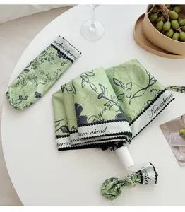 Detail view of the artistic green folding sun umbrella with floral print and portable sleeve.