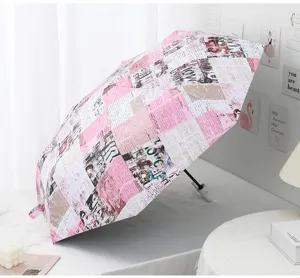 Automatic folding umbrella detail showing pink newspaper print fabric and compact handle design.