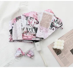 Automatic folding sun umbrella with pink newspaper print, UV protection, portable and chic.