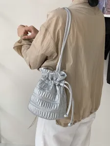 Detailed look at the trendy silver metallic ruched drawstring shoulder bag worn by a model.