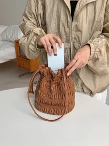 Detail view of a brown ruched drawstring bucket bag showing soft texture and shoulder strap.