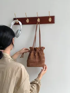 Brown pleated bucket bag detail shot showcasing unique drawstring design and texture for women.