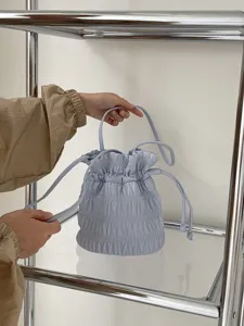 Detailed shot of light blue ruched bucket bag, featuring stylish drawstring and soft texture.