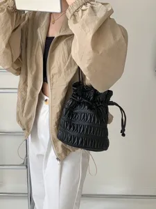 Detailed view of the stylish black pleated bucket bag with a chic drawstring closure.
