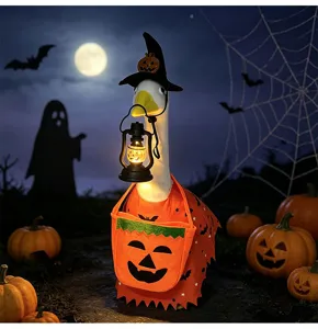 Detailed view of Halloween porch goose wearing pumpkin costume and holding glowing lantern.