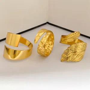 Primer plano de tres servilleteros de metal dorado con texturas lisas, martilladas y de hojas