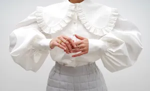 Close-up detail of white cotton blouse with ruffled Peter Pan collar and lantern sleeves