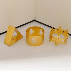 Detalle de tres servilleteros dorados con motivos de copo de nieve, árbol y remolino