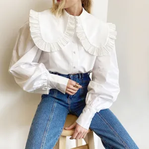 Detailed view of white blouse featuring oversized ruffled Peter Pan collar and puff sleeves