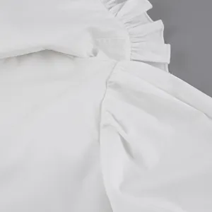 Macro detail view of white cotton puff sleeve blouse featuring delicate ruffle collar trim