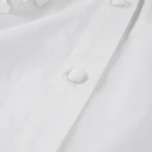 Macro close-up of fabric texture and covered buttons on a white cotton blouse detail
