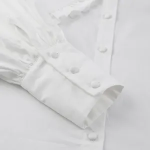 Close-up detail of white cotton shirt showing the buttoned cuff and fabric texture