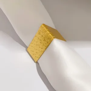Primer plano detallado de servilletero de metal dorado con motivos grabados en espiral