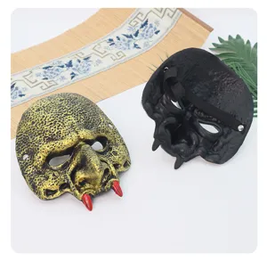 Close-up detail van het goblin halfmasker met goud getextureerde voorkant, rode hoektanden en band.