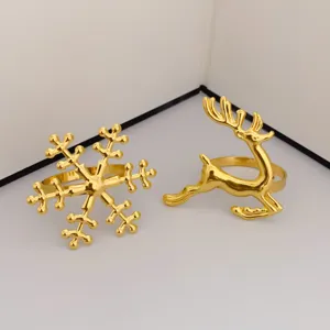 Primer plano de servilleteros de metal dorado con formas de copo de nieve y de reno.
